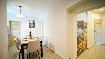 Un comedor con mesa y sillas de madera, una lámpara colgante y un cuadro en la pared.