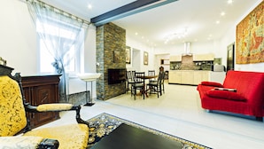 A spacious living room with a red sofa, a dining area, a kitchen, and a fireplace. - Apartamenty EverySky Luxor Karkonoska (Karpacz)