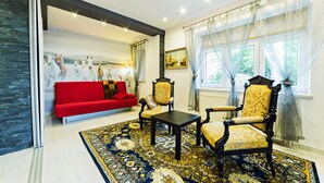A living room with a red sofa, two ornate chairs, a coffee table, and a patterned rug. - Apartamenty EverySky Luxor Karkonoska (Karpacz)