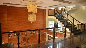 A spacious lobby with a wooden wall, a staircase, and a glass railing. - Sterling Banquet and Hotel (Palampur)