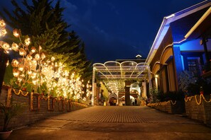 An entrance with a brick pathway, decorative lights, and a covered area with a glass roof. - Sterling Banquet and Hotel (Palampur)