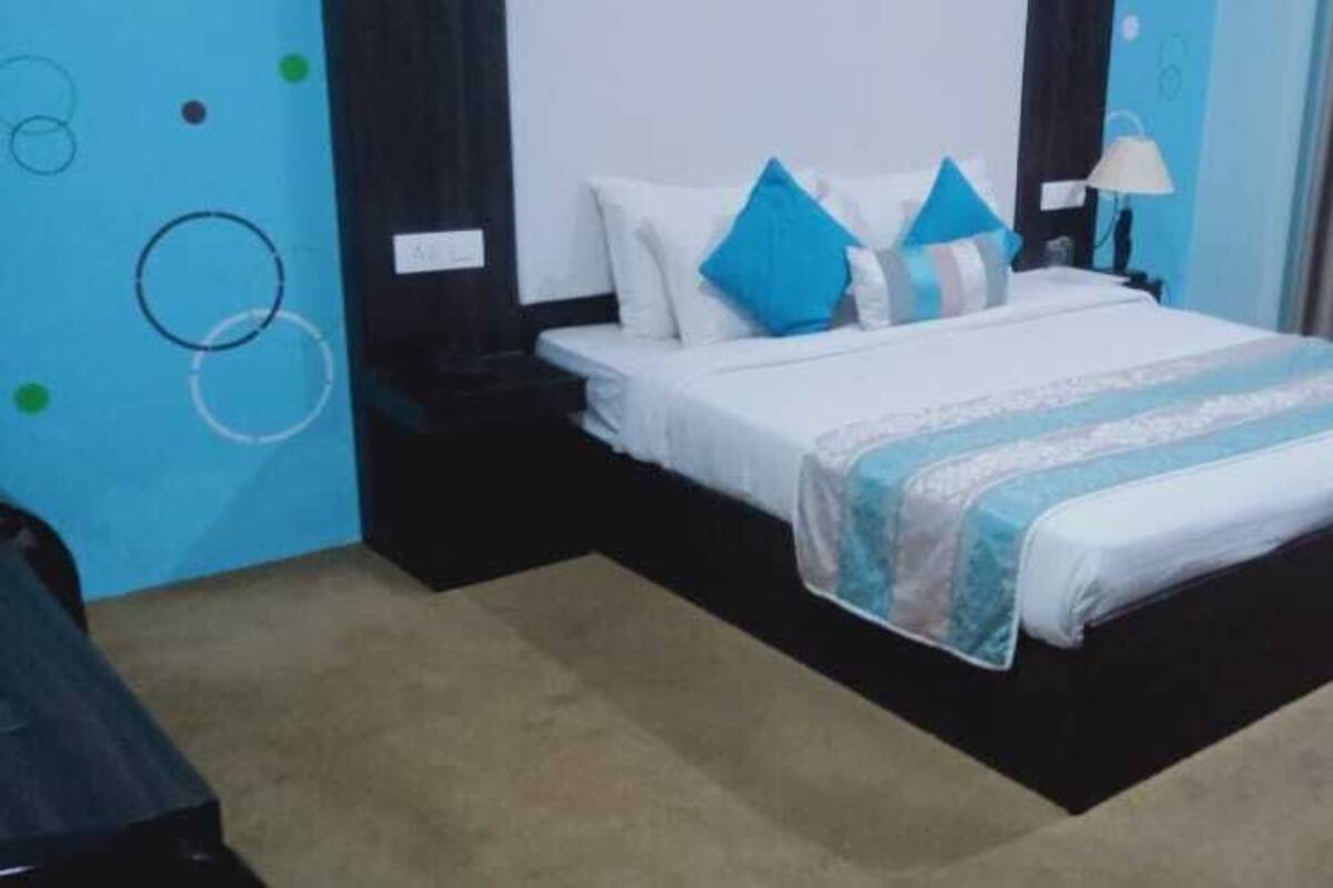 A hotel room with a bed, a nightstand, a lamp, and a curtain.