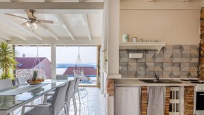 A modern kitchen with a brick accent wall, a hanging chair, and a dining area with a glass table and chairs.