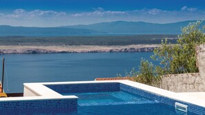A swimming pool with a view of a body of water and distant mountains.