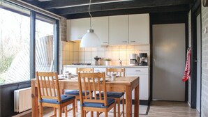 Una cocina moderna con armarios blancos, una mesa de comedor de madera con sillas y una lámpara colgante.