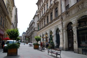 A historic street with ornate buildings, benches, and a café. - Opera Theater Apartment (Budapest)