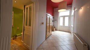 Un corridoio con una parete verde, una porta bianca, un armadietto in legno e un termosifone.