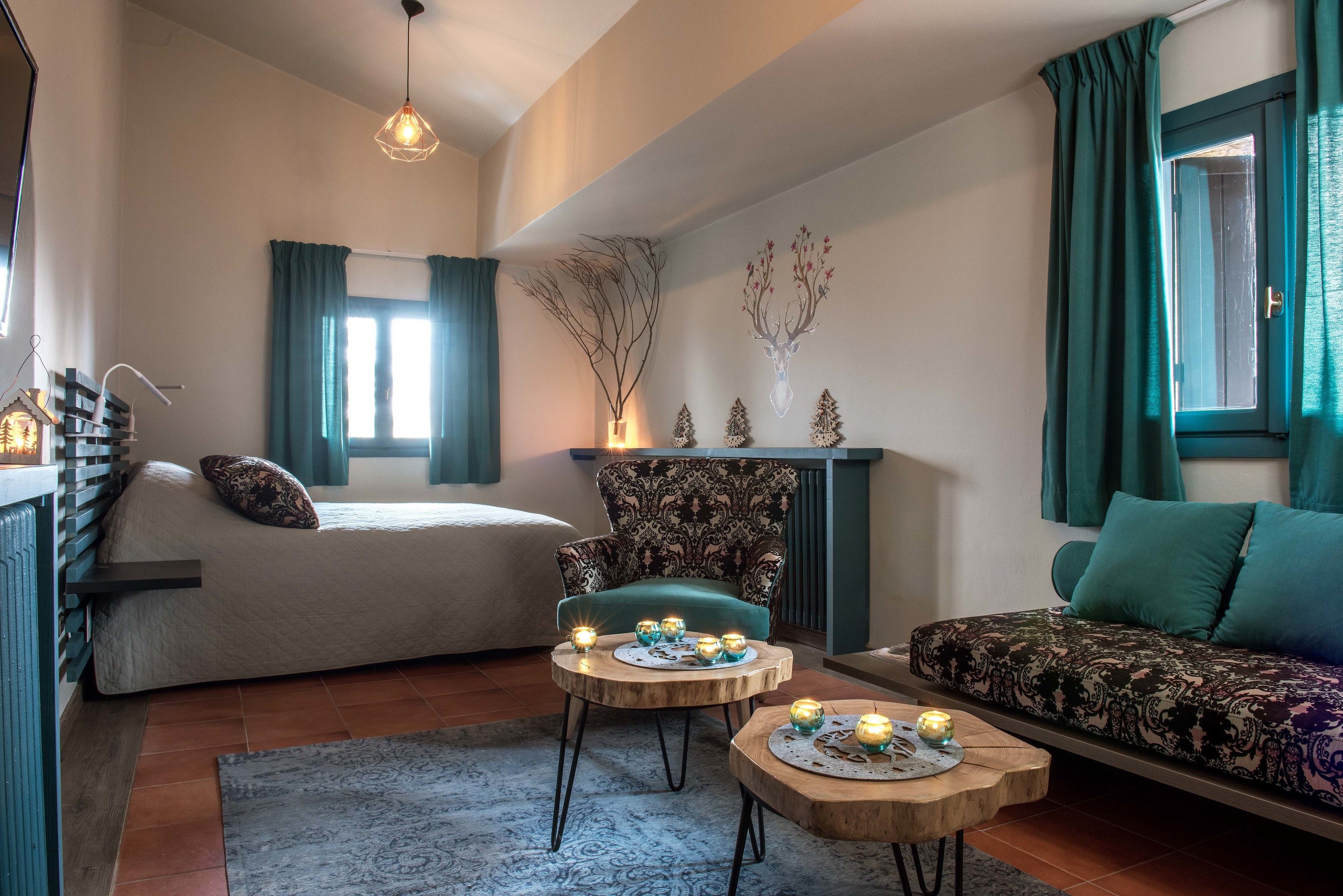 Un salon chaleureux avec un lit, un fauteuil à motifs, un canapé et une cheminée agrémentée d’objets décoratifs.