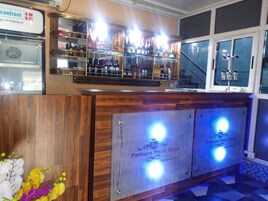 Una zona de bar con estanterías llenas de botellas y un cartel del Hotel Fortune Pearl.