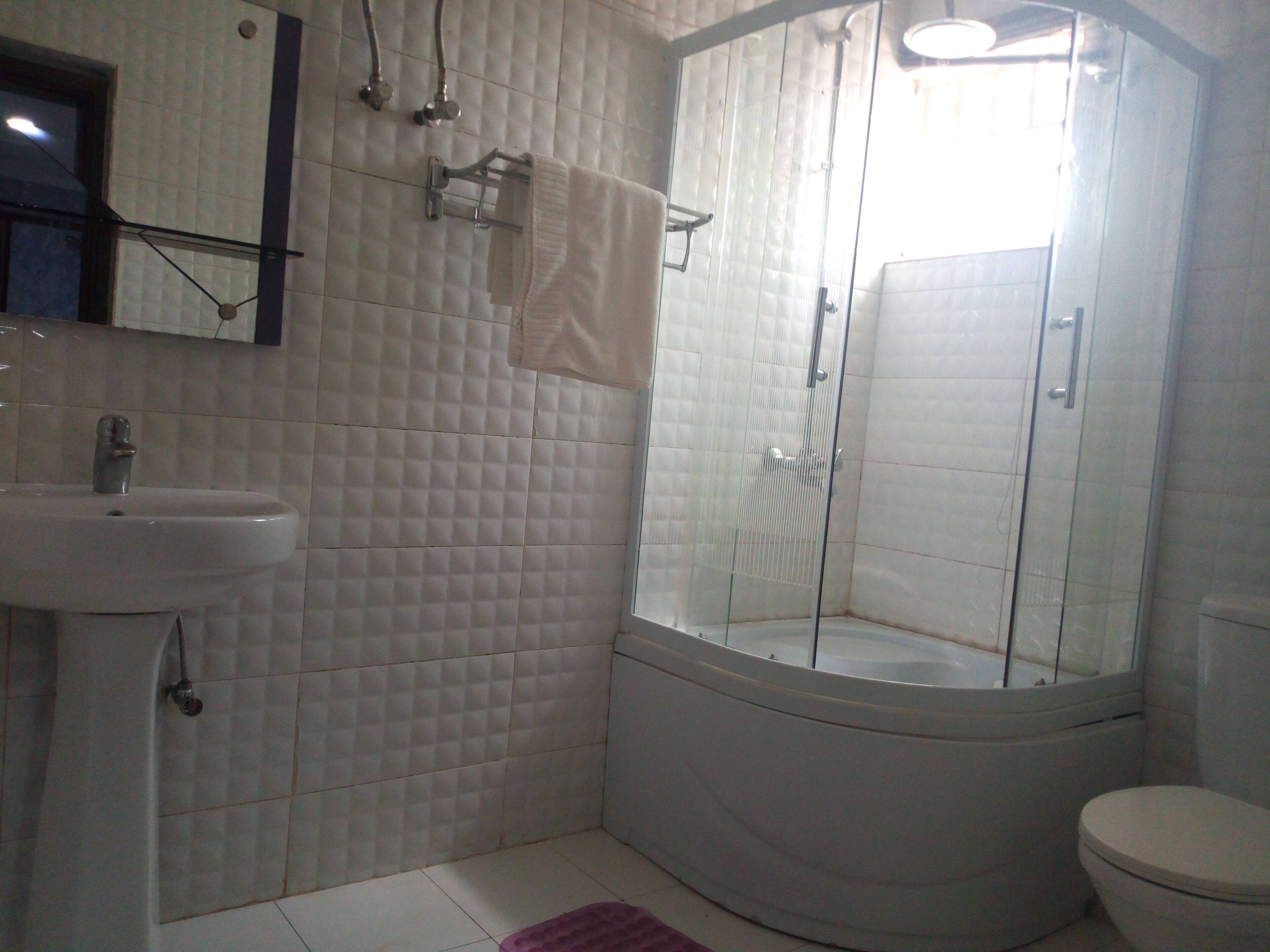 Casa de banho com lavatório branco, cabine de duche com vidro e sanita.