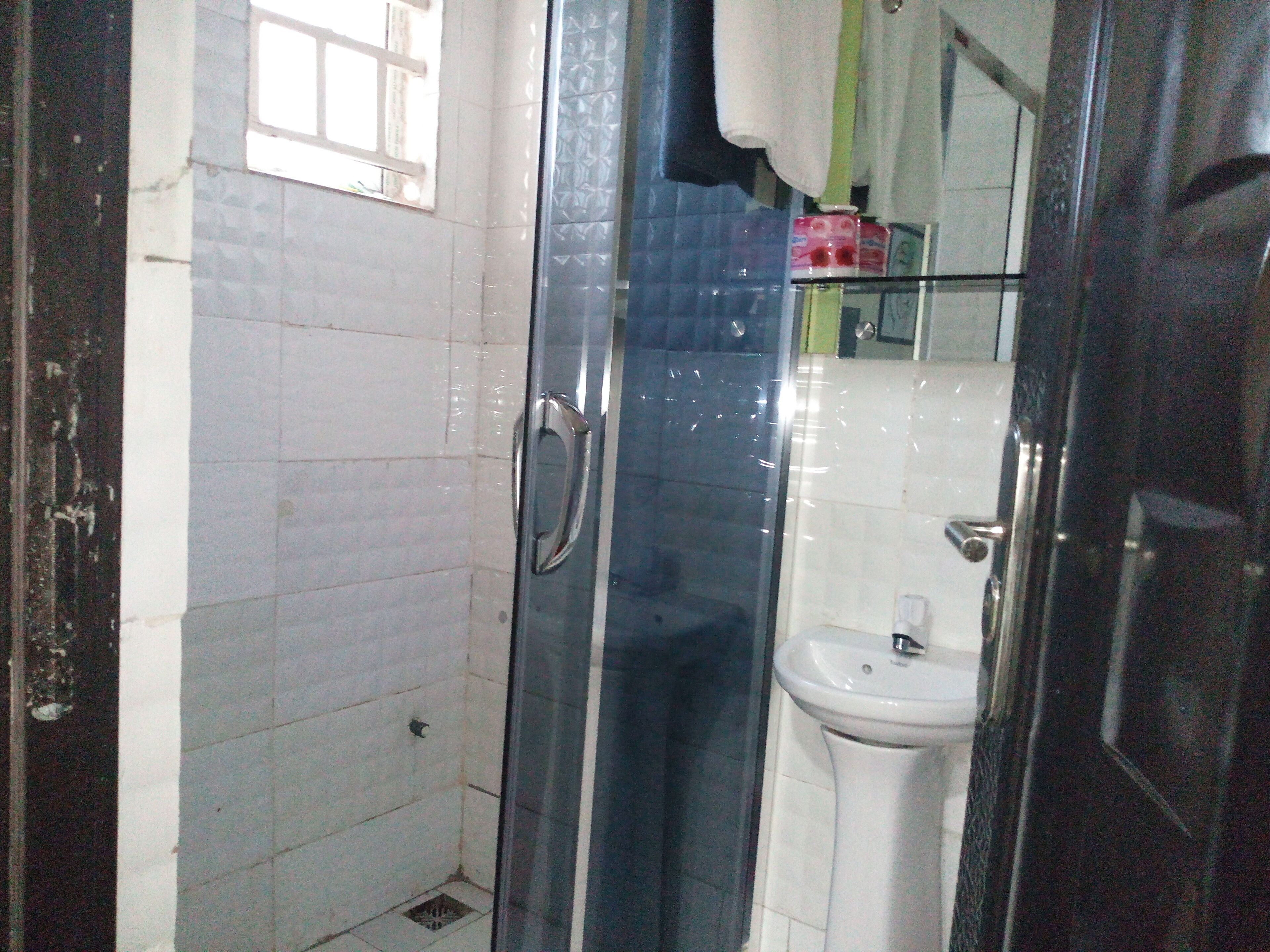Un baño con cabina de ducha de vidrio, un lavabo blanco y un espejo.