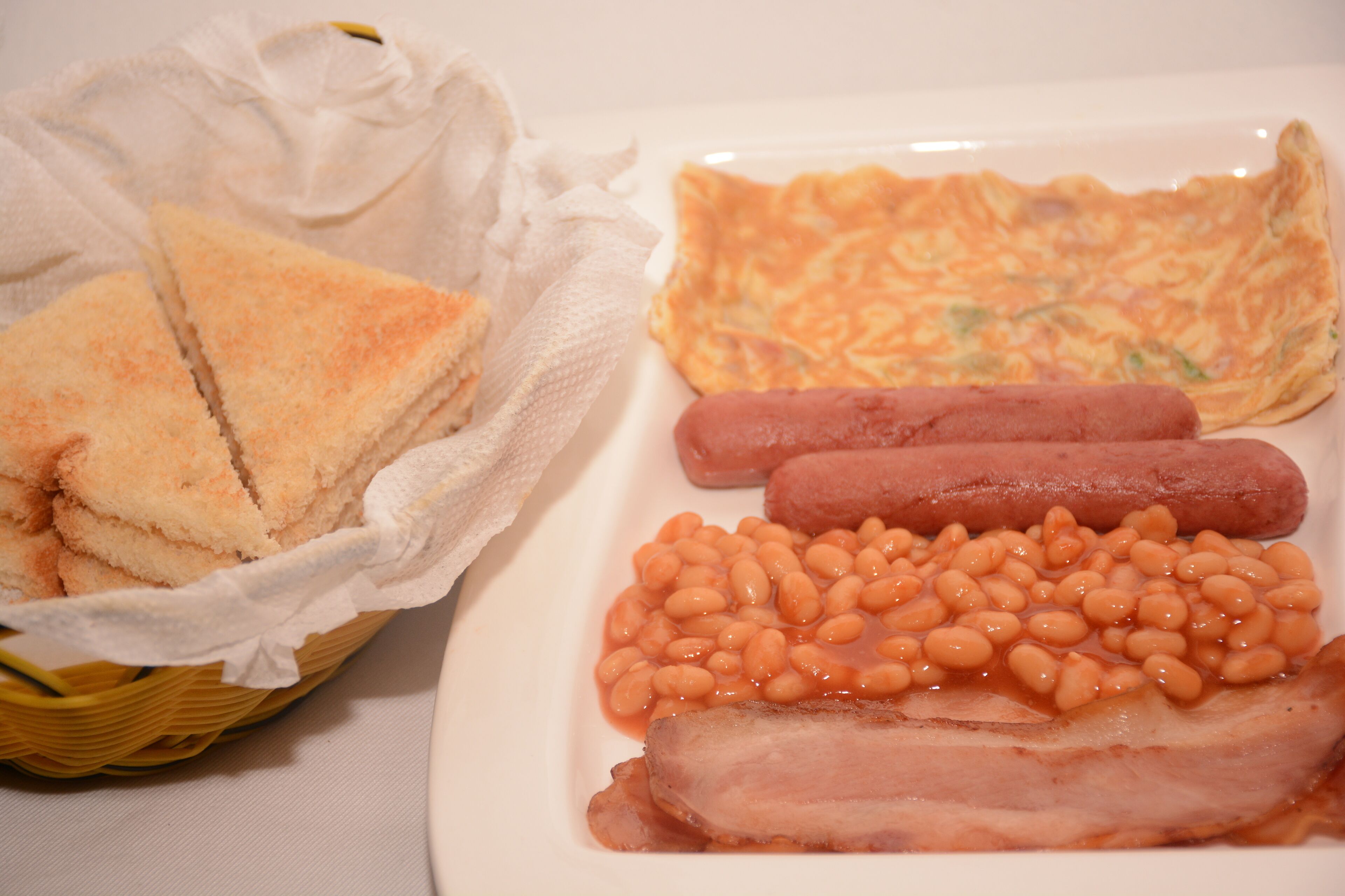Un piatto con pane tostato, fagioli, pancetta e salsicce.