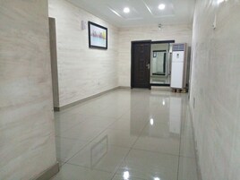 Un pasillo con piso de baldosas, un cuadro en la pared y una puerta que da a otra habitación.