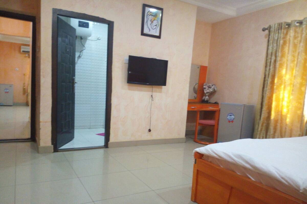 Una habitación de hotel con una cama, un escritorio, un televisor y una puerta que da a un baño.