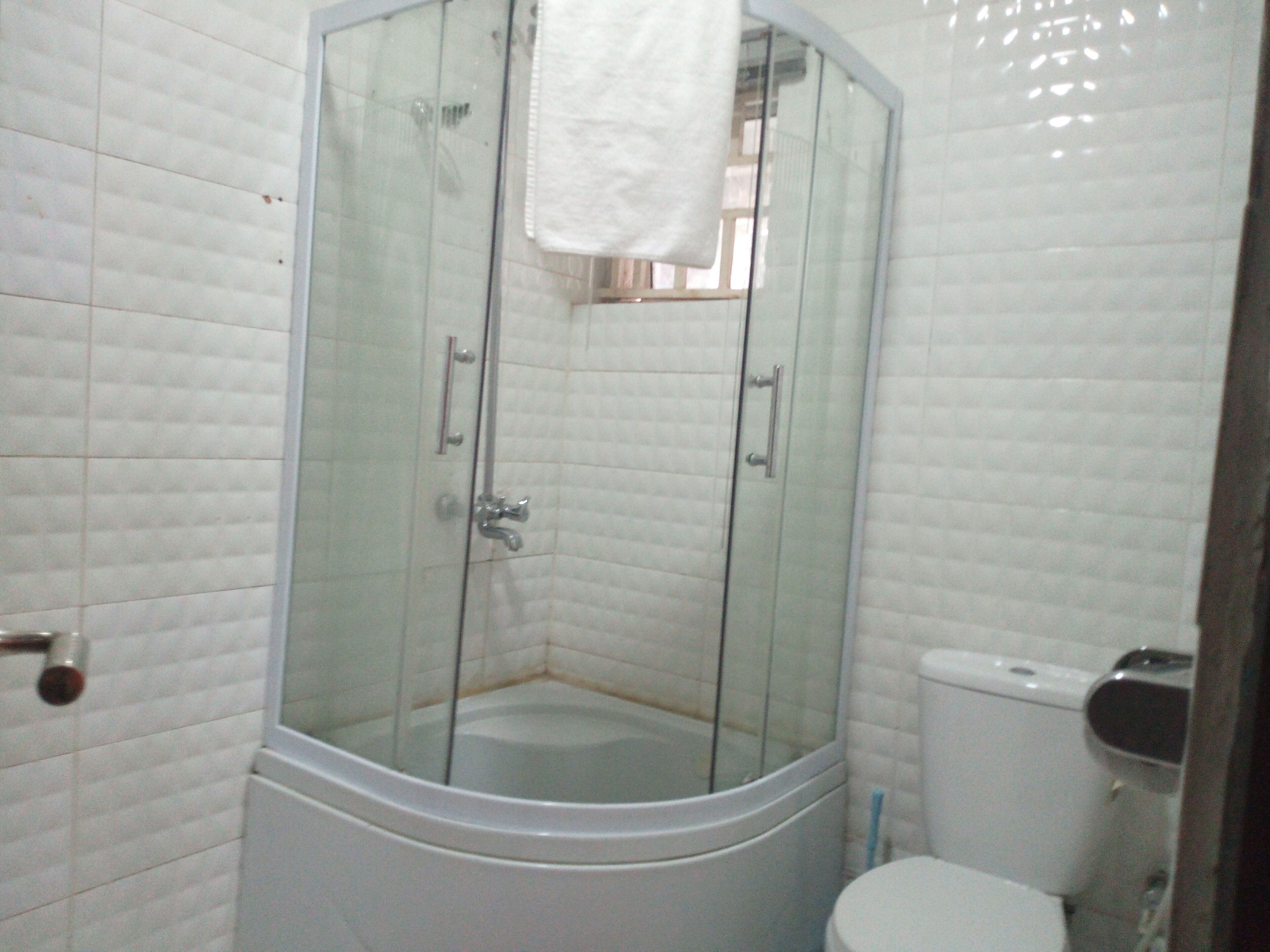 Un baño con ducha de vidrio, inodoro y lavamanos.
