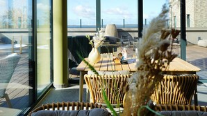 A modern outdoor seating area with wicker chairs, a wooden table, and a vase with dried plants. - Beautiful apartment in Lembruch/Dümmer See with indoor swimming pool (Lembruch/Dümmer See)