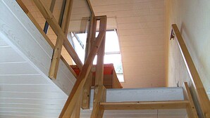 Een houten trap die leidt naar een vide met een dakraam.
