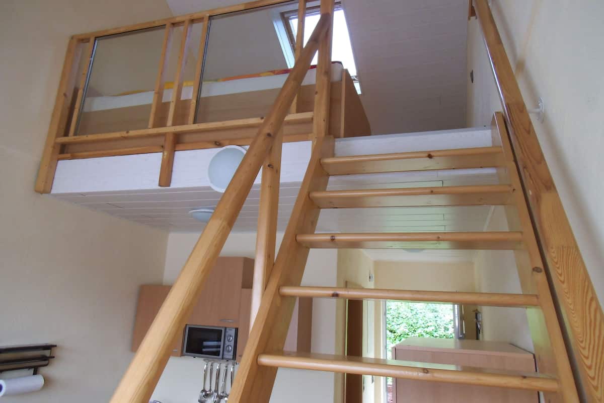 Une chambre en mezzanine en bois à plusieurs niveaux, avec un lit en mezzanine et un escalier.