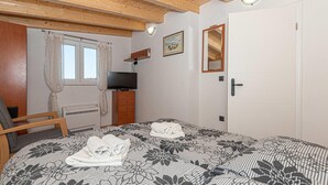 Een slaapkamer met een bed, een televisie, een kaptafel, een stoel en een deur.