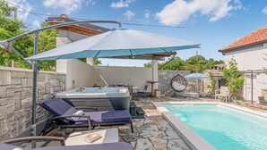 Een privé zwembadgedeelte met ligbedden, een jacuzzi en parasols.