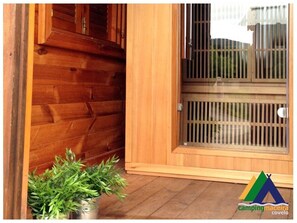 A wooden exterior with a sliding glass door and a potted plant. - Camping Maceira (Covelo)
