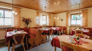 Un ristorante con panche e tavoli in legno, apparecchiati con posateria e un vaso di fiori.