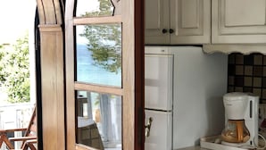 A kitchen with white cabinets, a refrigerator, and a coffee maker. - Byblos Mare (Thasos)