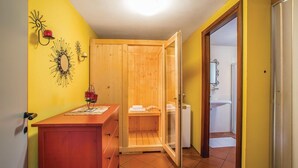 Ein kleines Badezimmer mit einer Holzsauna, einem Waschbecken und einem Spiegel.