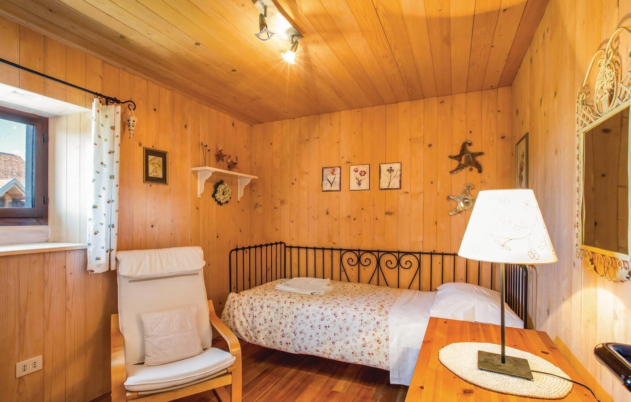 Une pièce chaleureuse en bois, avec un lit, une chaise, une table et une fenêtre avec des rideaux.