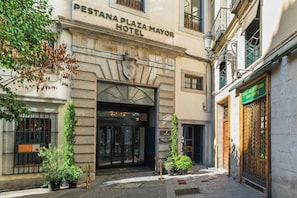 The entrance to the PESTANA PLAZA MAYOR HOTEL with a stone facade, a coat of arms, and a traditional wrought iron gate.