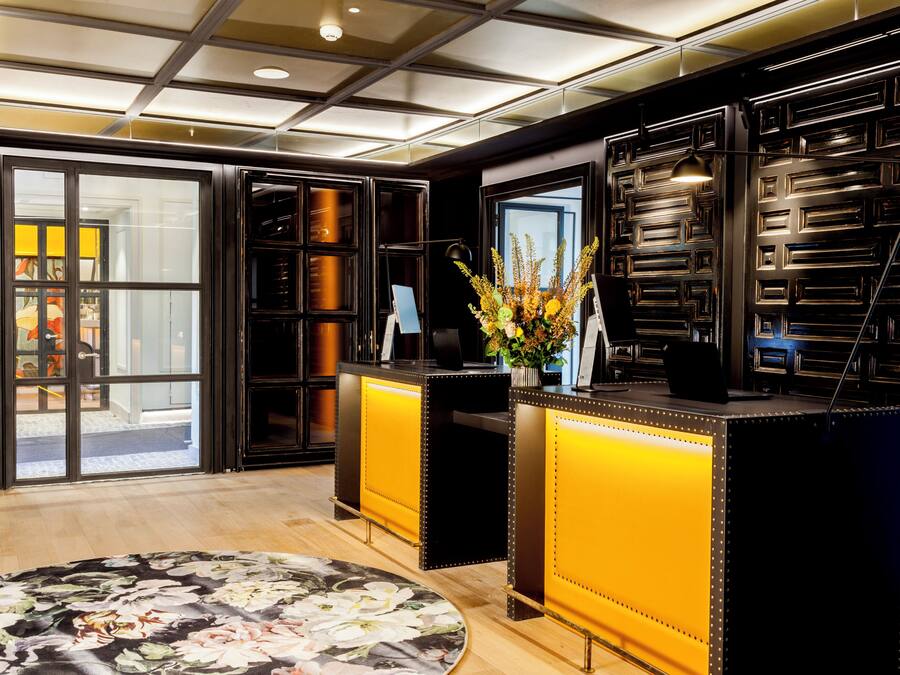 A reception area with a glass door entrance, a reception desk, and a large floral rug.