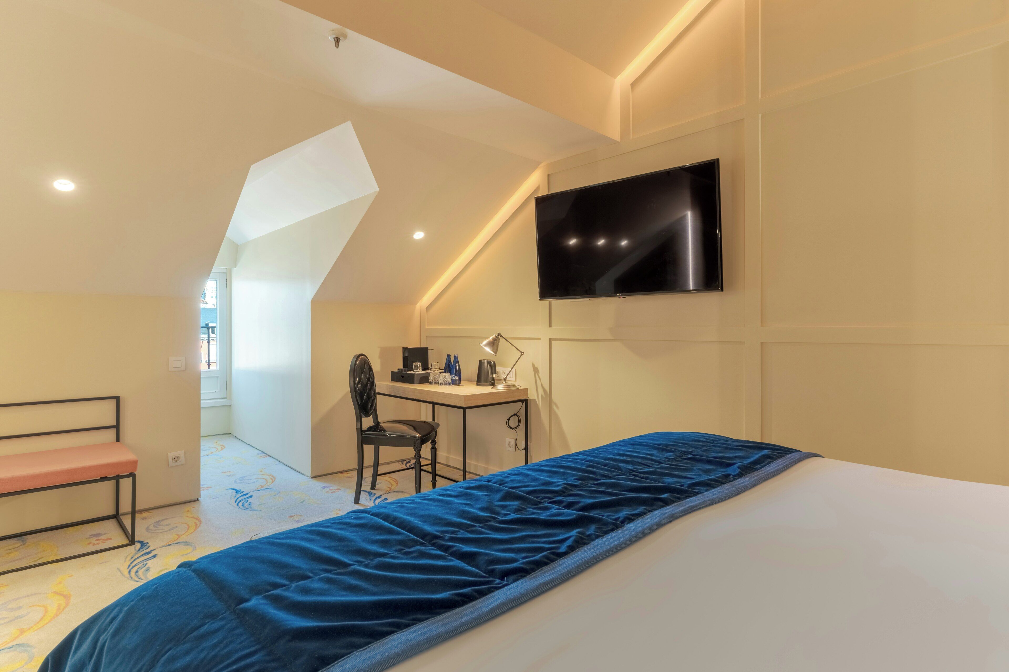 Una camera d'albergo con un letto, una scrivania, una sedia, una televisione e una finestra.
