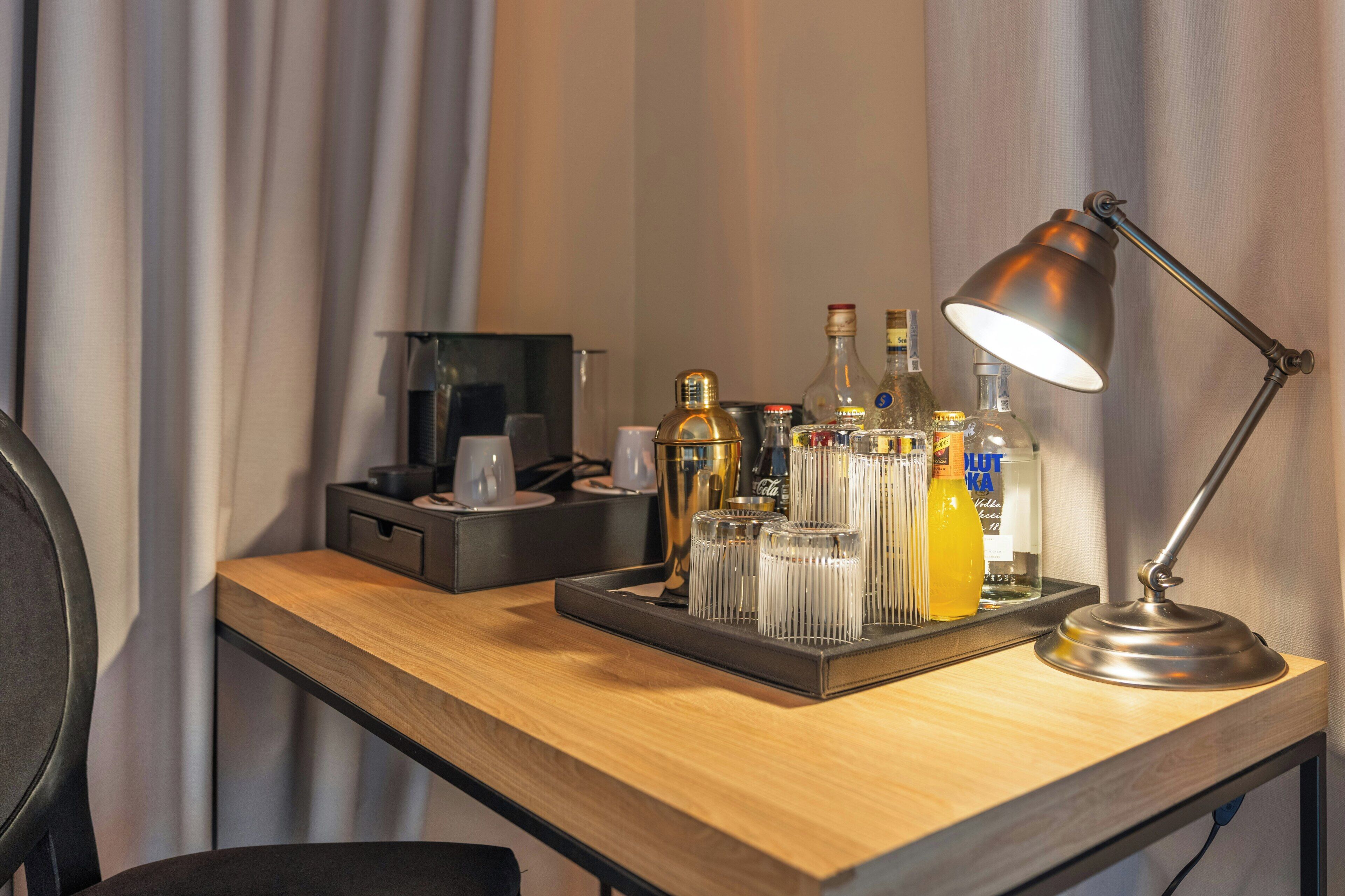 A desk with a tray holding various bottles, glasses, and a lamp.