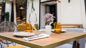 Un'area pranzo interna con un tavolo di legno apparecchiato per due, circondato da sedie.