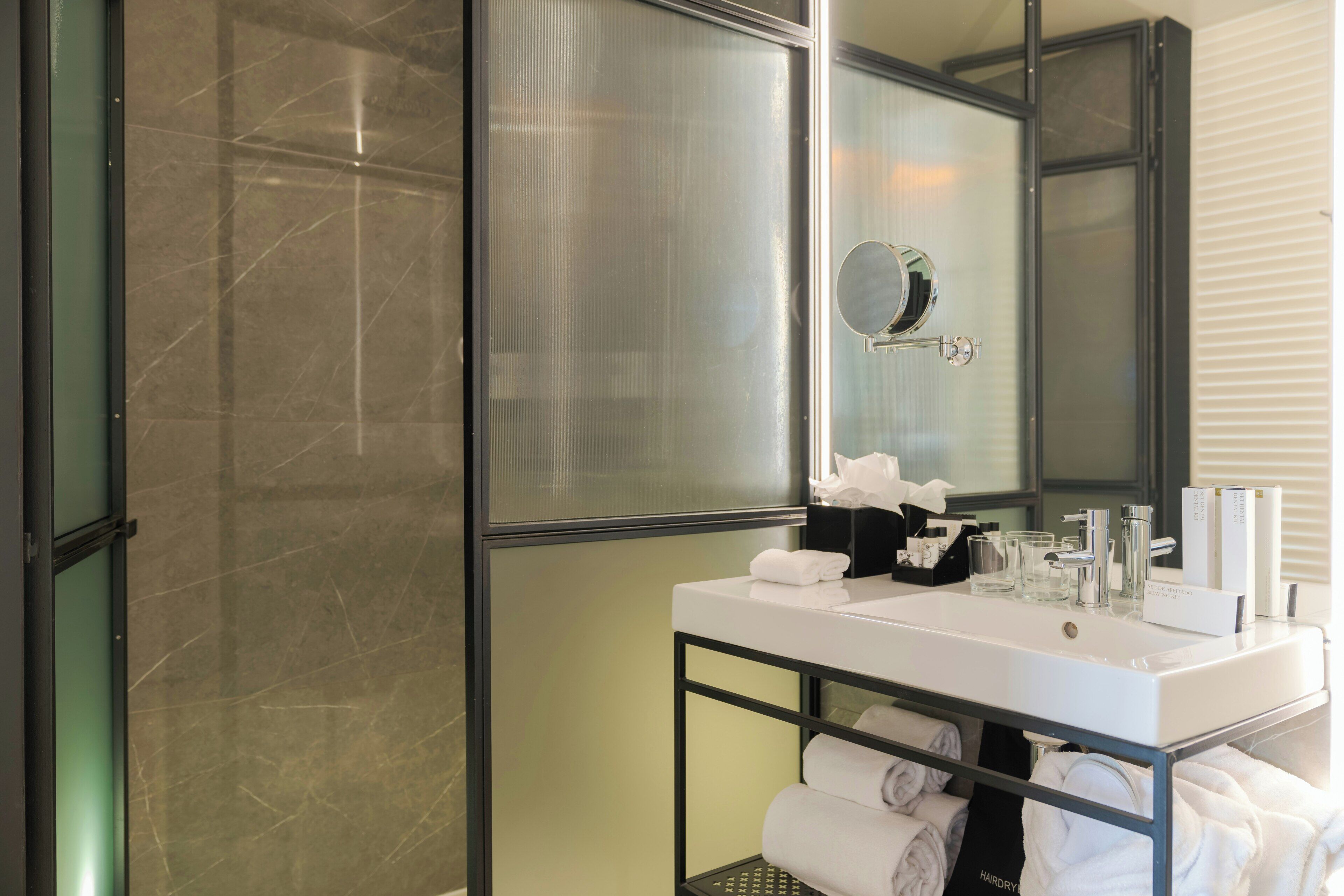 A modern bathroom with a glass shower enclosure, a white sink with a mirror, and neatly arranged towels.