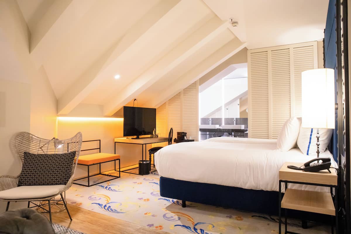Une chambre d’hôtel équipée d’un lit, d’un bureau, d’une chaise et d’un téléviseur.