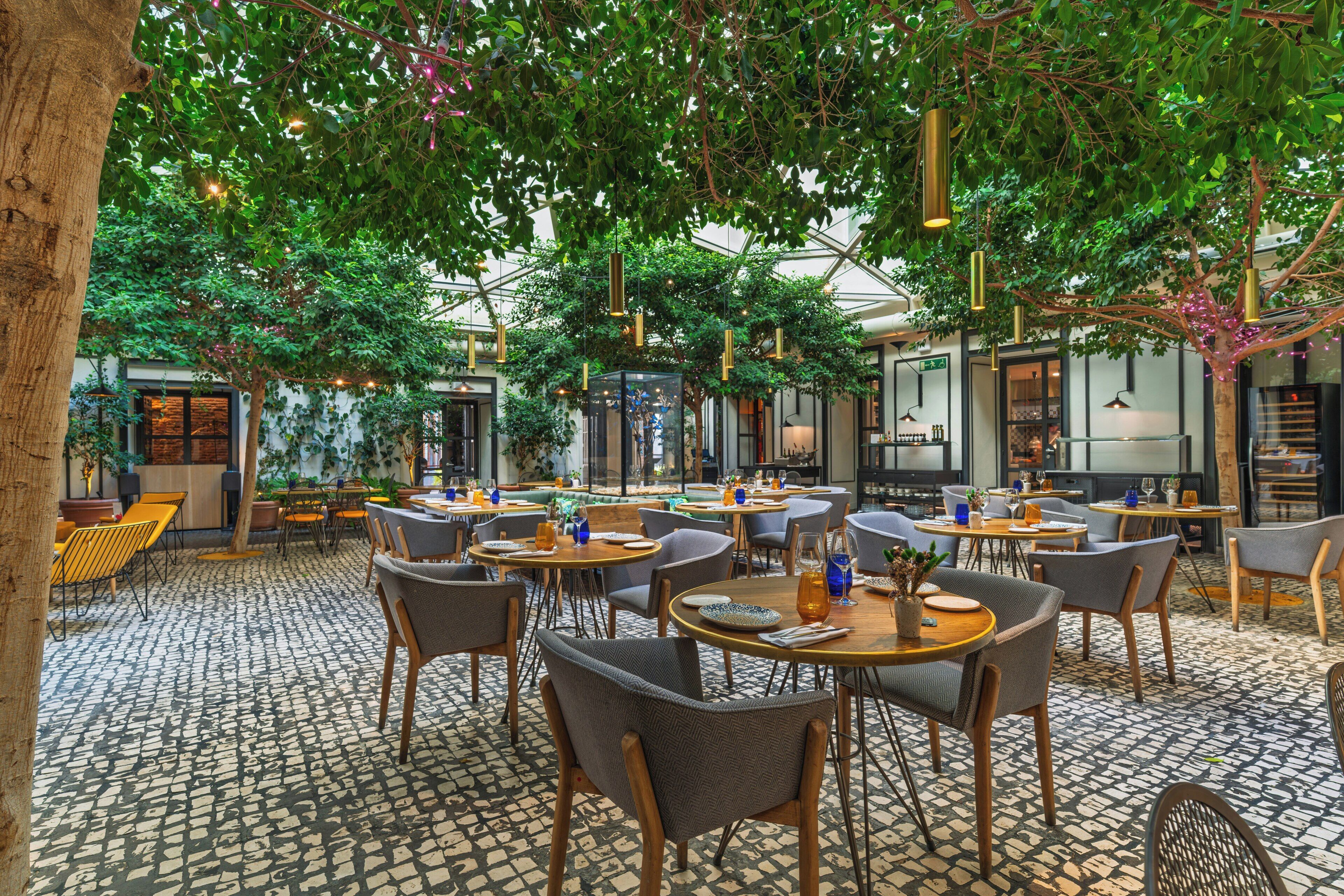 Un comedor interior con mesas y sillas, un suelo estampado y luces colgantes.