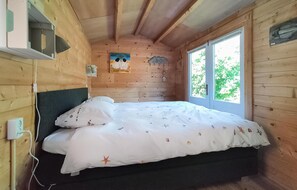 Cozy bedroom with a bed, window, and wall-mounted shelf.