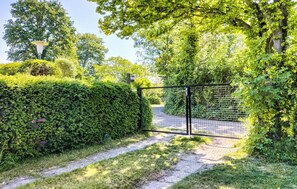 Stroll through the serene garden pathway to a peaceful entrance, surrounded by lush greenery and mature trees.