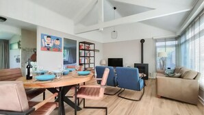 Un salon moderne comprenant un coin repas, une cheminée et une bibliothèque.