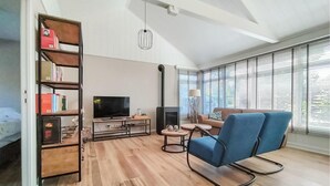 Un salon moderne avec un téléviseur, une bibliothèque, un fauteuil bleu et une cheminée.