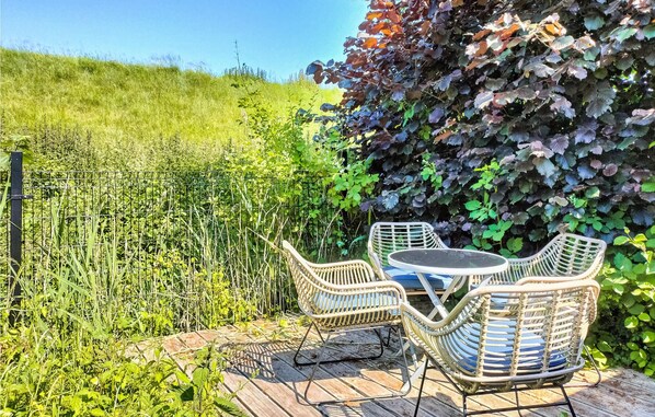 Relax in a serene garden setting with a patio featuring a wicker table and chairs.