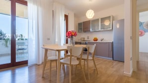 A modern kitchen with wooden cabinets, a stainless steel refrigerator, and a dining area with a table and chairs. - Appartamento 5th Floor (Cagliari)