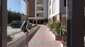 A modern building with a tiled walkway leading to a parking area. - Appartamento 5th Floor (Cagliari)