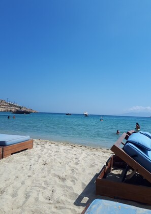 A beach with clear blue water, people swimming, and lounge chairs on the sand. - Private Vacation Home - Near Mykonos New Port (Mykonos)