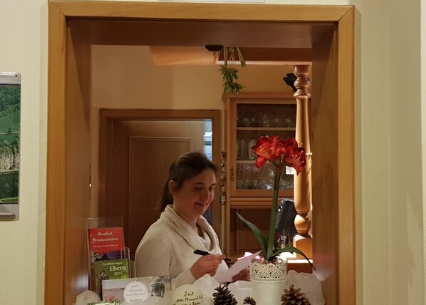 Una persona en un escritorio con un libro, un florero con flores y un cartel con texto.