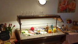 A buffet setup with various food items and beverages, including fruits, cheeses, and juices. - Gasthof Frankenstuben (Ebern)