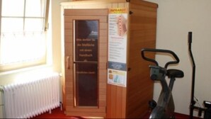 A sauna room with a sign reading "INFRAROT ARMSTARK" and a window. - Gasthof Frankenstuben (Ebern)