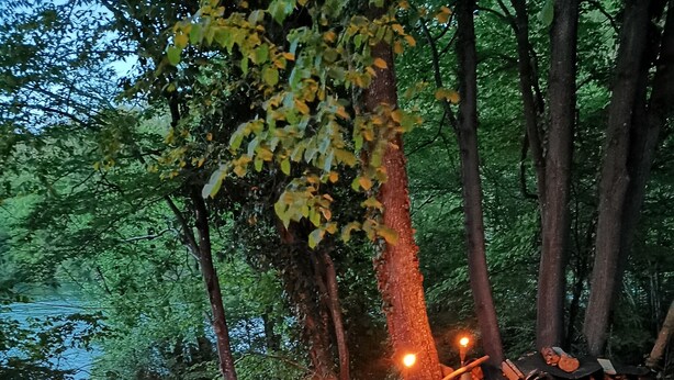 A wooden deck with tables and stools overlooking a river, surrounded by trees. - Riverland (Duga Resa)