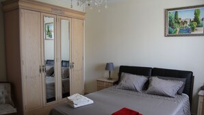 A bedroom with a large wardrobe, a bed with grey bedding, a red towel, and a painting on the wall. - Casa flamenca en El Ventorrillo (Cullar Vega)